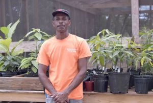 One of the Beacon Farm staff standing in front of some potted plants.