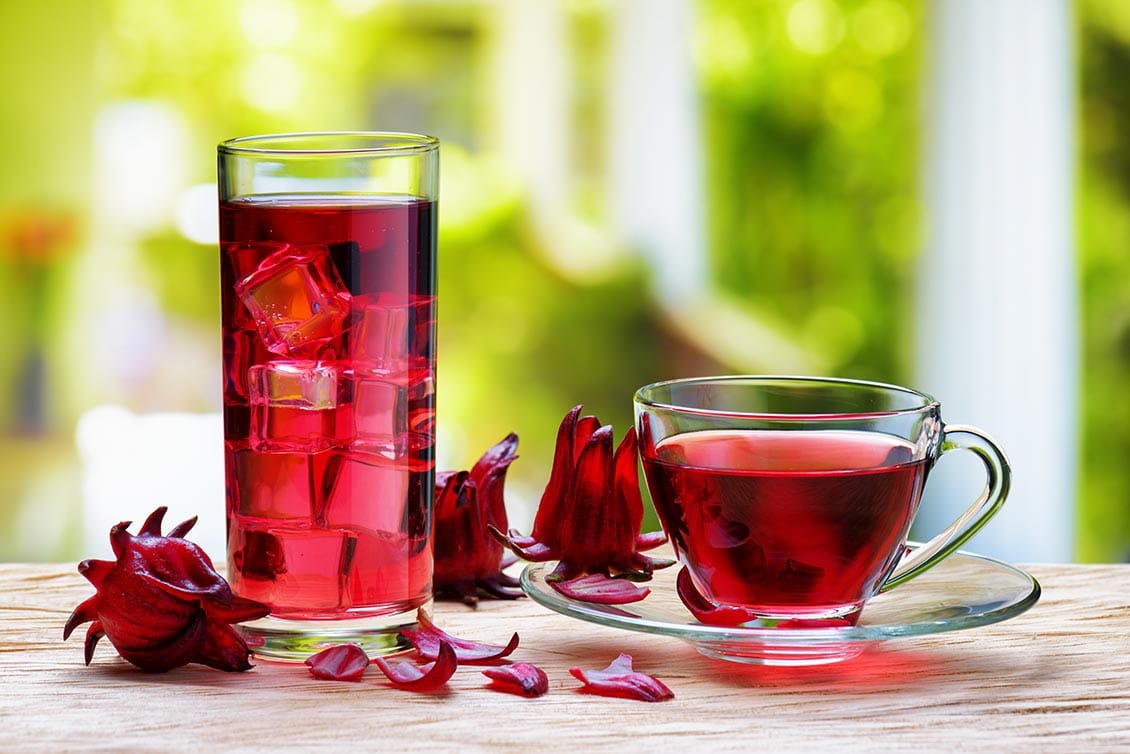 Glass decanter and cup and saucer filled with Iced Sorrel, a Caymanian classic seasonal drink.