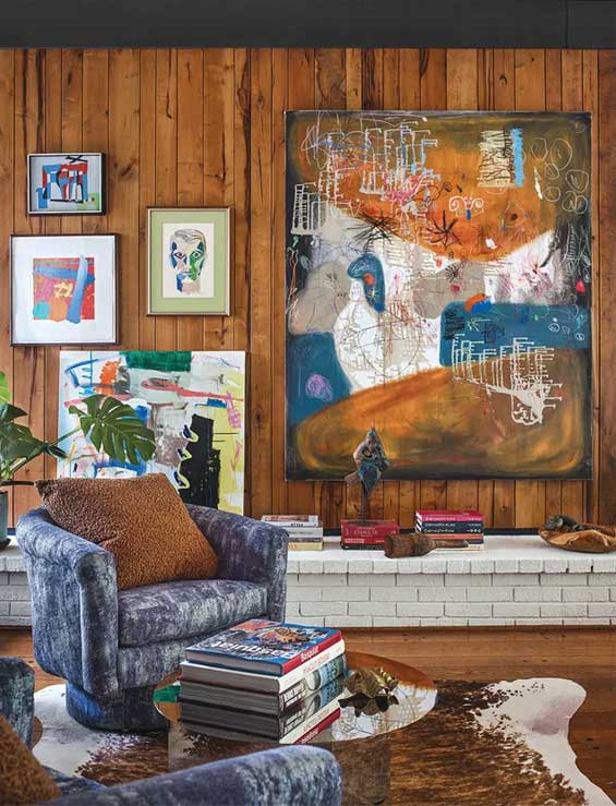 A small reading area with some modern art on the wood panelled wall.