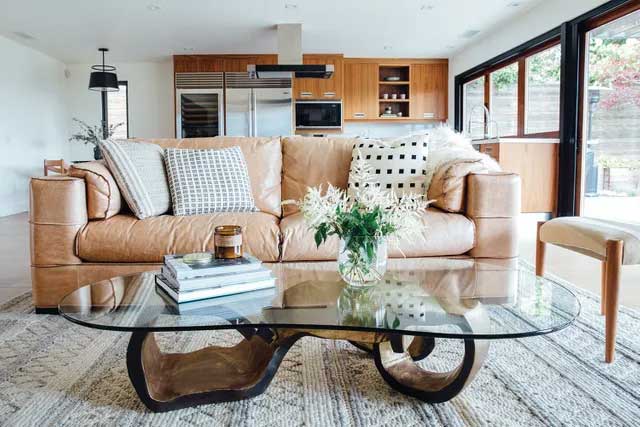 A leather sofa with coffee table in foreground and kitchen in the background.