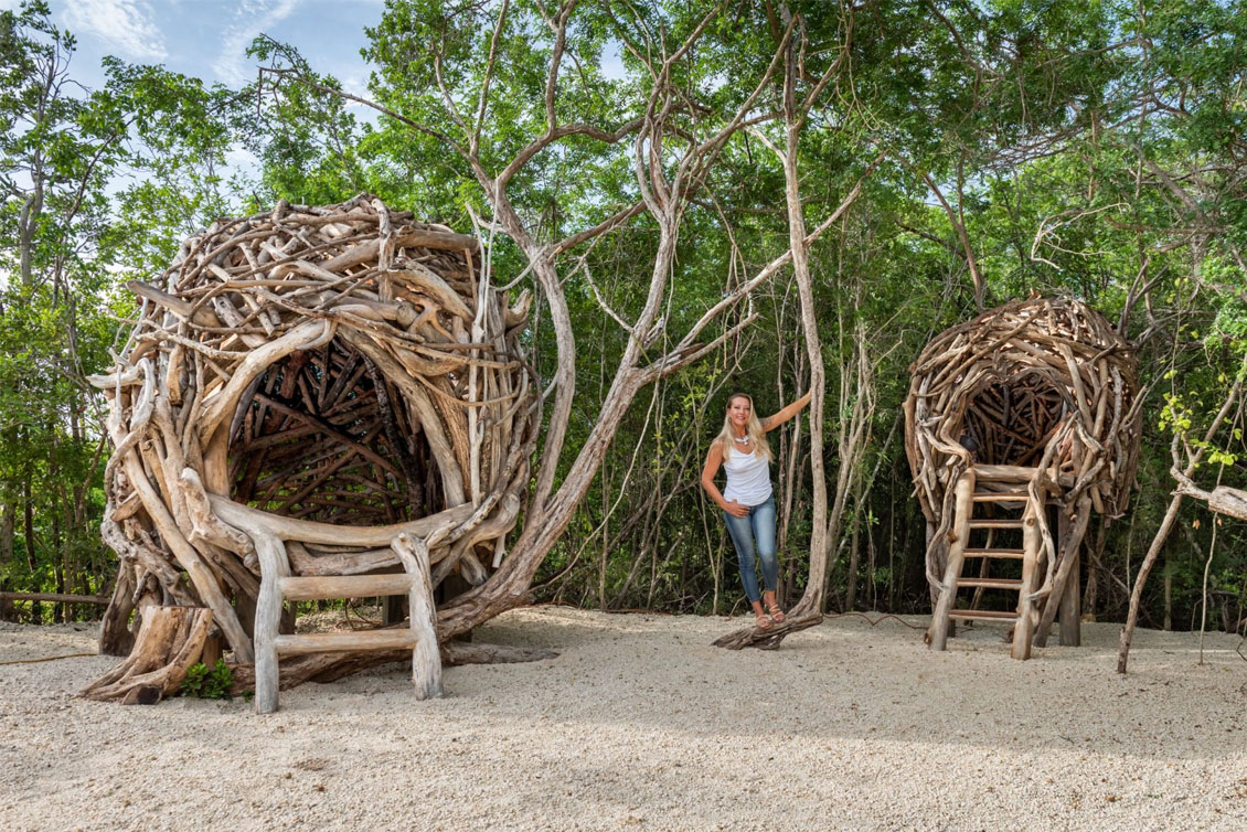 Artist Tansy Maki next to her bird nest sculptures situated within the Queen Elizabeth II Botanic Park in Grand Cayman.