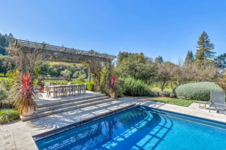 Pool area with open dining area and gardens.