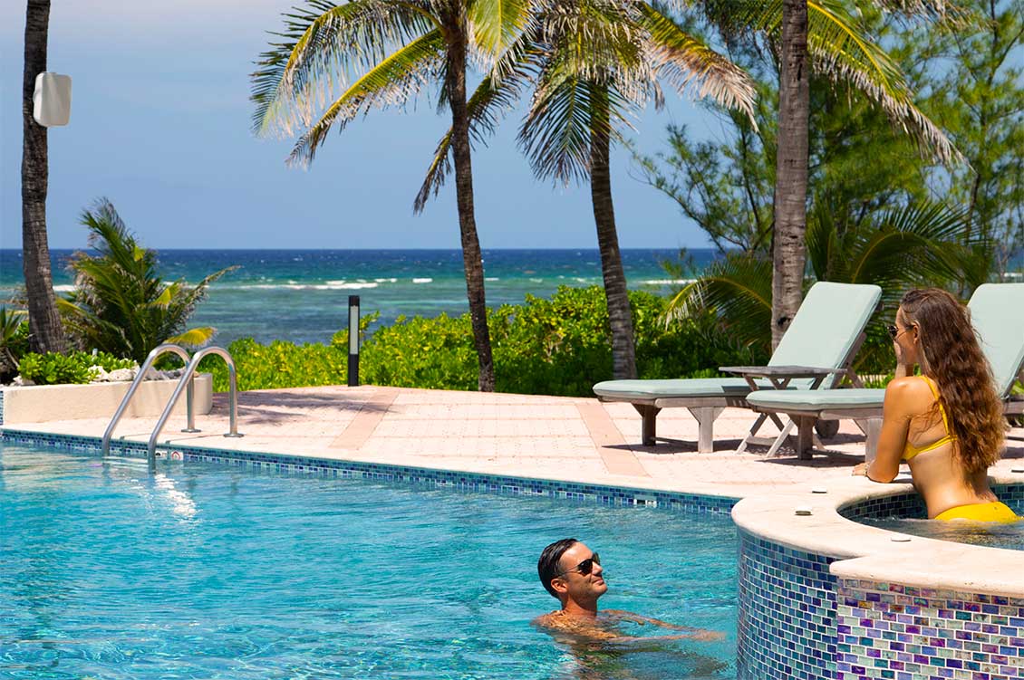 A couple enjoying a dip in the pool and hot tub at Blue Water Therapy on Grand Cayman,