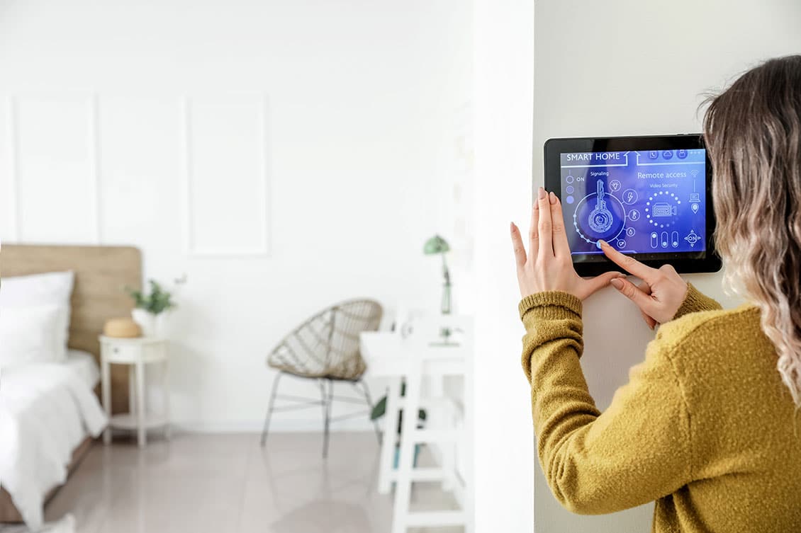 A woman activating smart home systems from a home domotics system.