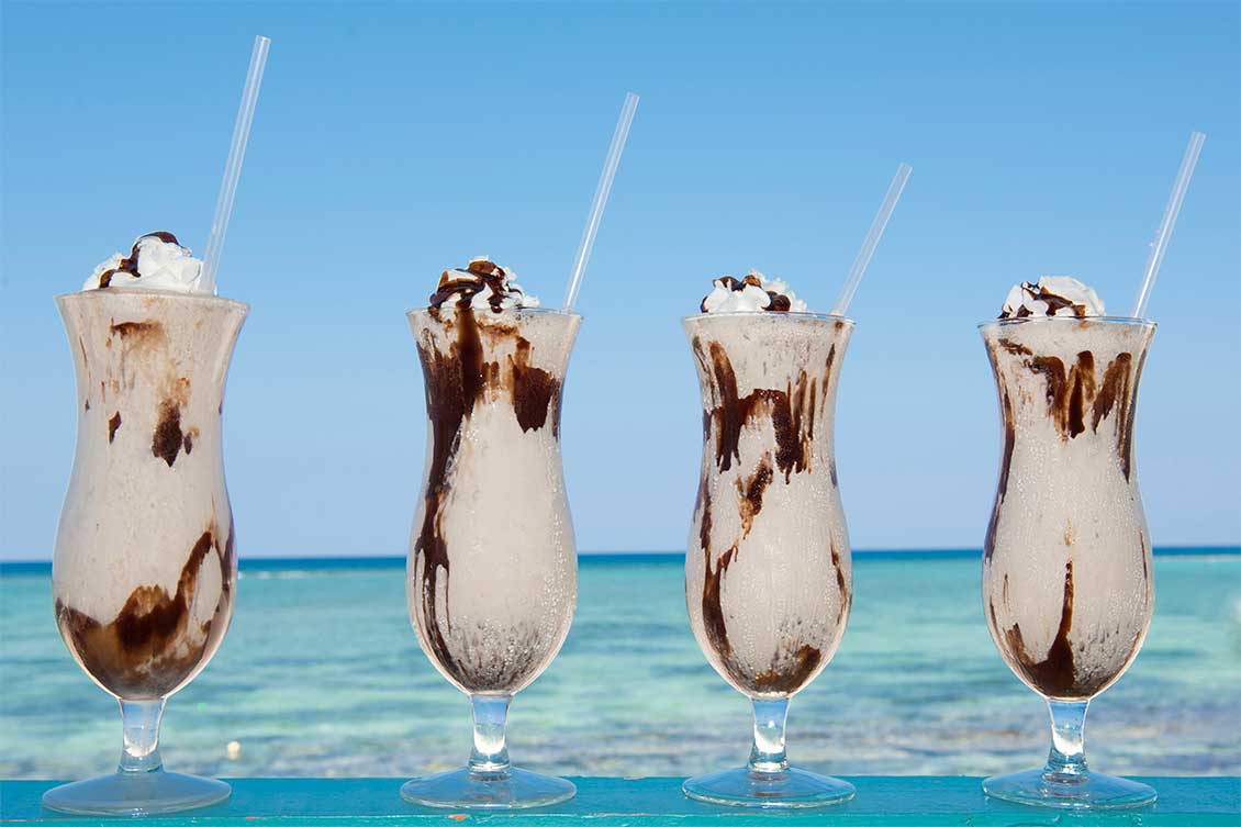 A row of Mudslide cocktails with the Caribbean Sea in the background.