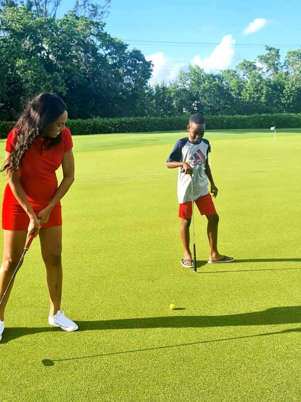 A wonan and son golfing on a putting green.