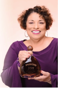 A smiling Joy Spence displaying an Appleton estate Reserve rum.