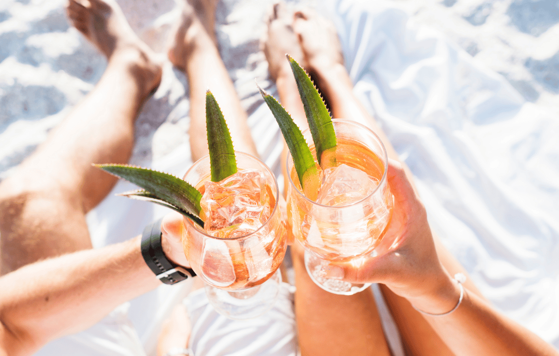 A couple toasting each other with cocktails.