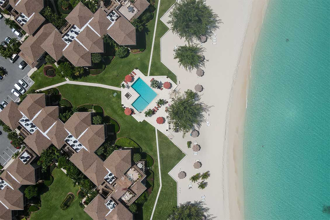 Aerial shot of Plantana's beachfront pool area and sea of Seven Mile Beach, Grand Cayman.