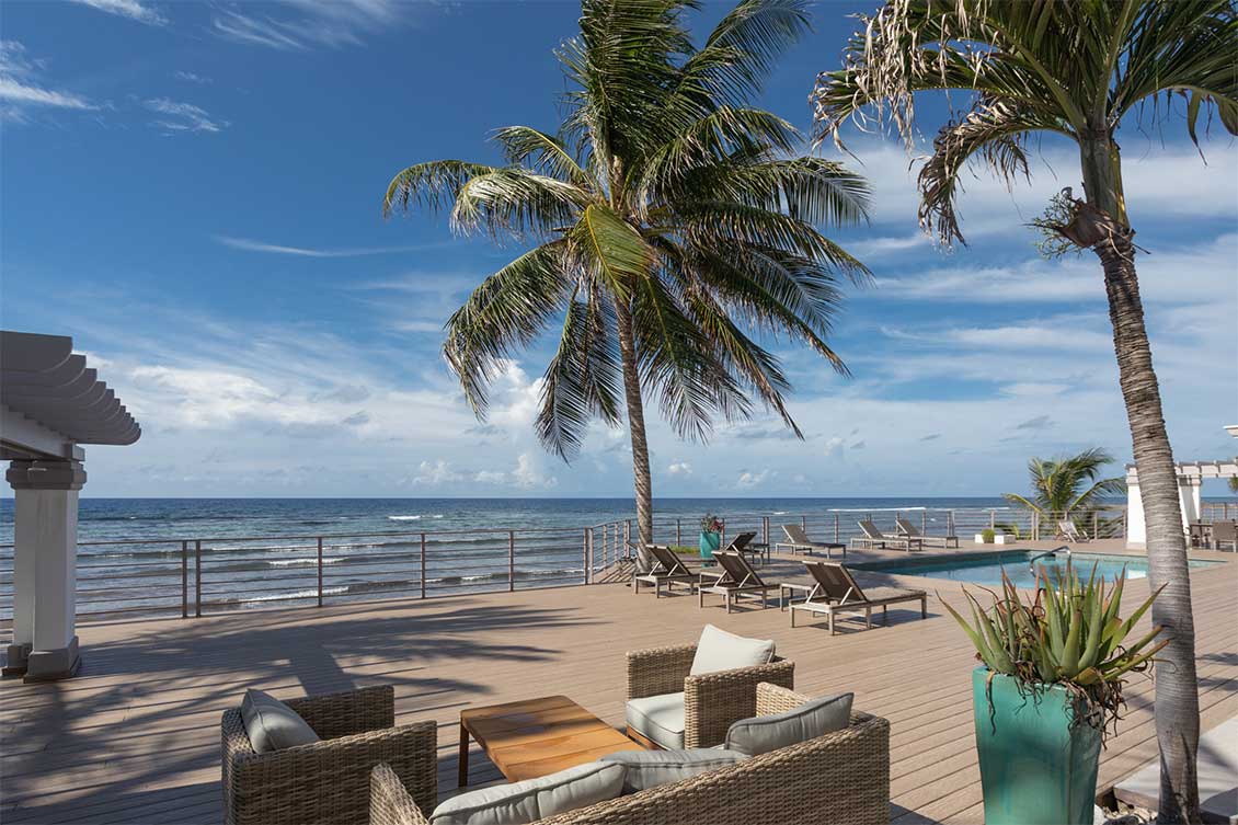 Ground level photo of the deck and pool of Prospect Grove ith the Caribbean Sea in the background.