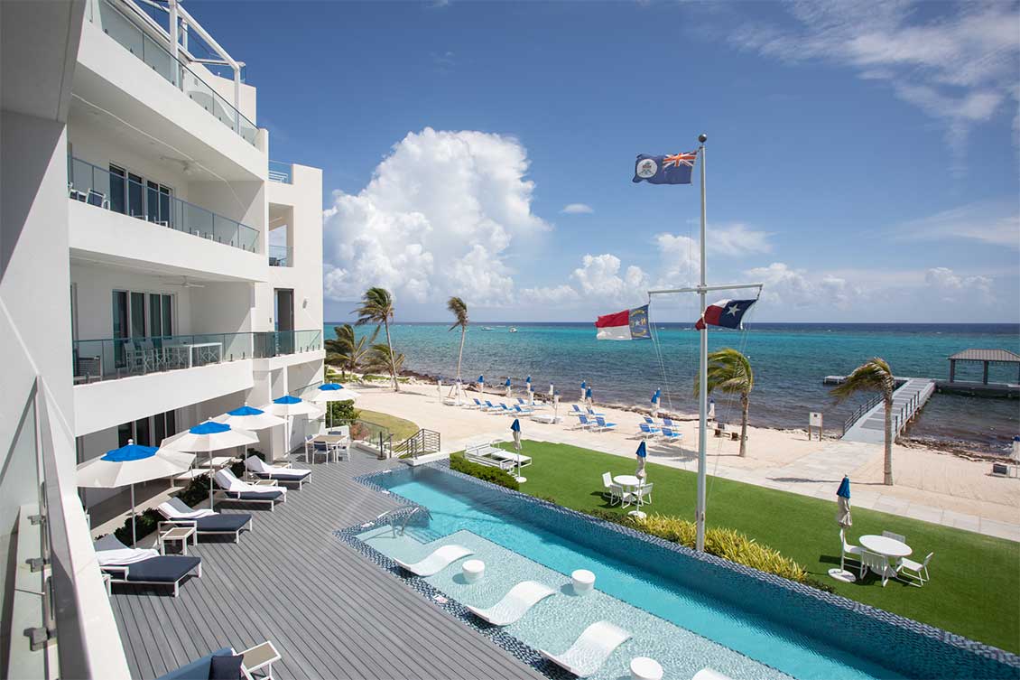 Balcony vie over Rum Point Club pool to the jetty and Caribbean Sea.