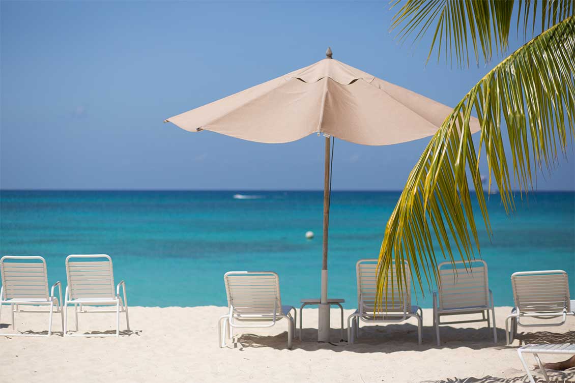 Sun loungers under an umbrella on Seven Mile Beach