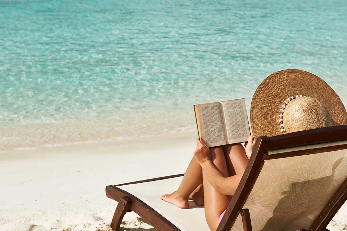 Woman reading a book on a longer in the Cayman Islands